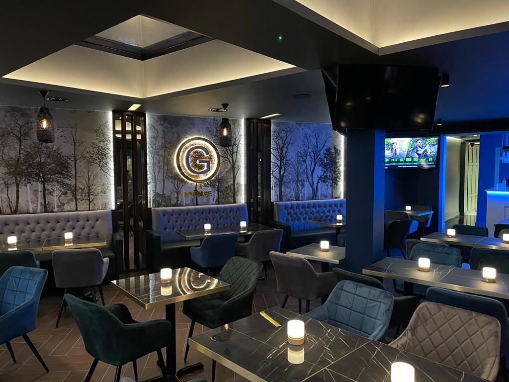 G Lounge: blue velvet banquette seating beneath the illuminated G wall