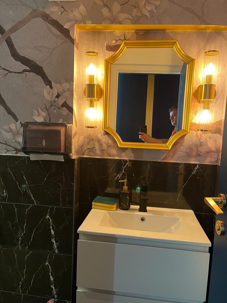 G Lounge: WC vanity with gold-framed mirror and marble tiling