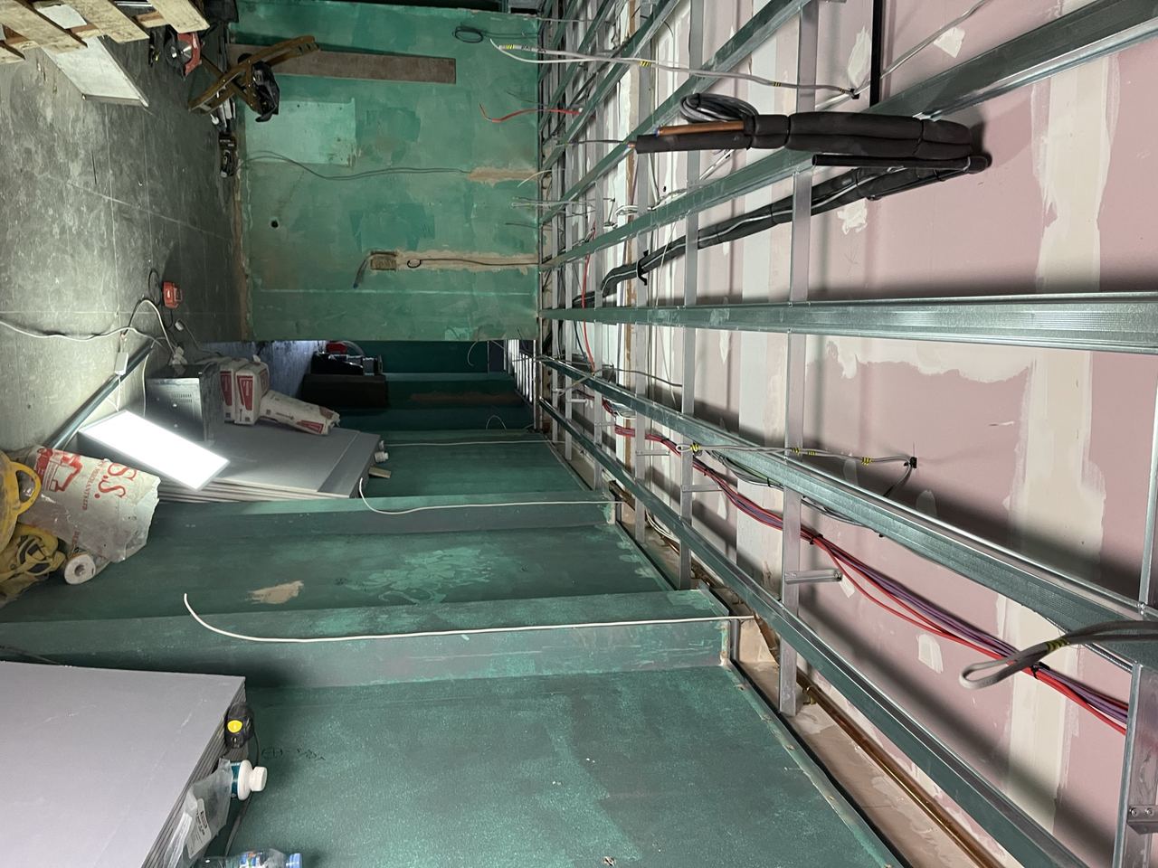 First-fix electrics and plumbing run through the open ceiling before closing up.